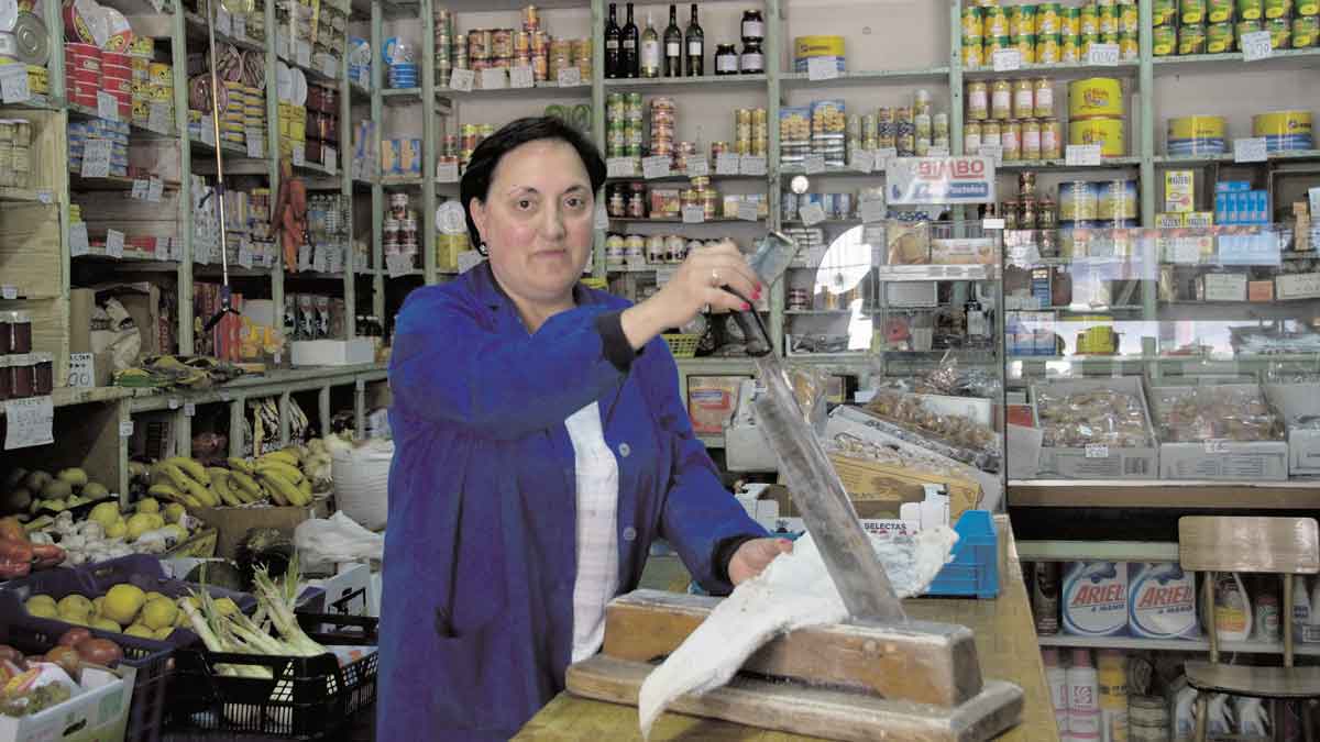 Amor Benavides partiendo el bacalao con la tradicional guillotina, aún en la vieja tienda. | MAURICIO PEÑA