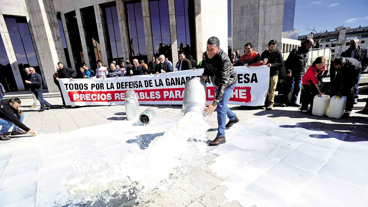 Un ganadero derrama una cántara de leche en una protesta. | DANIEL MARTÍN