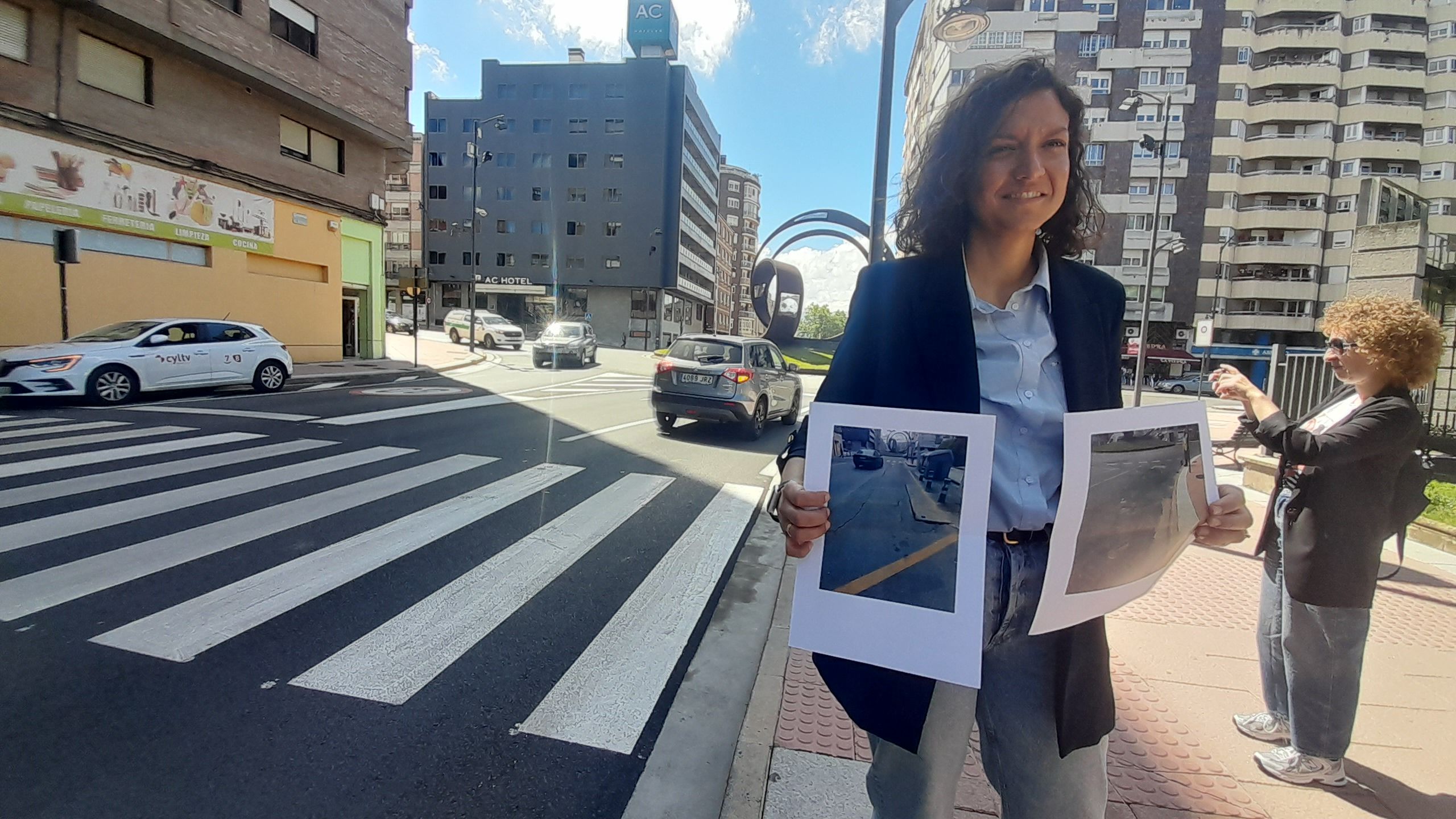 Lidia Coca ante el nuevo asfaltado, mostrando imágenes del socavón que se ha eliminado. | MAR IGLESIAS