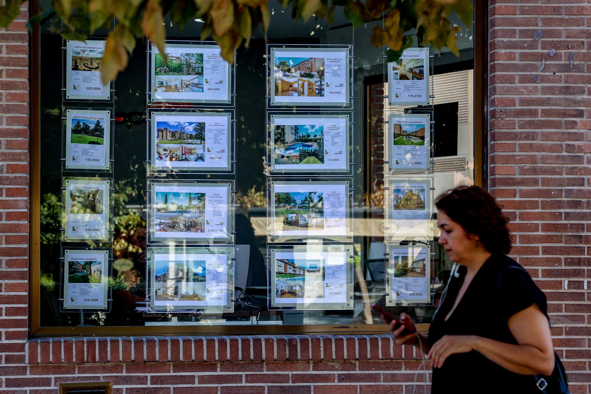 Una mujer camina frente a un escaparate de anuncios de vivienda. | EUROPA PRESS