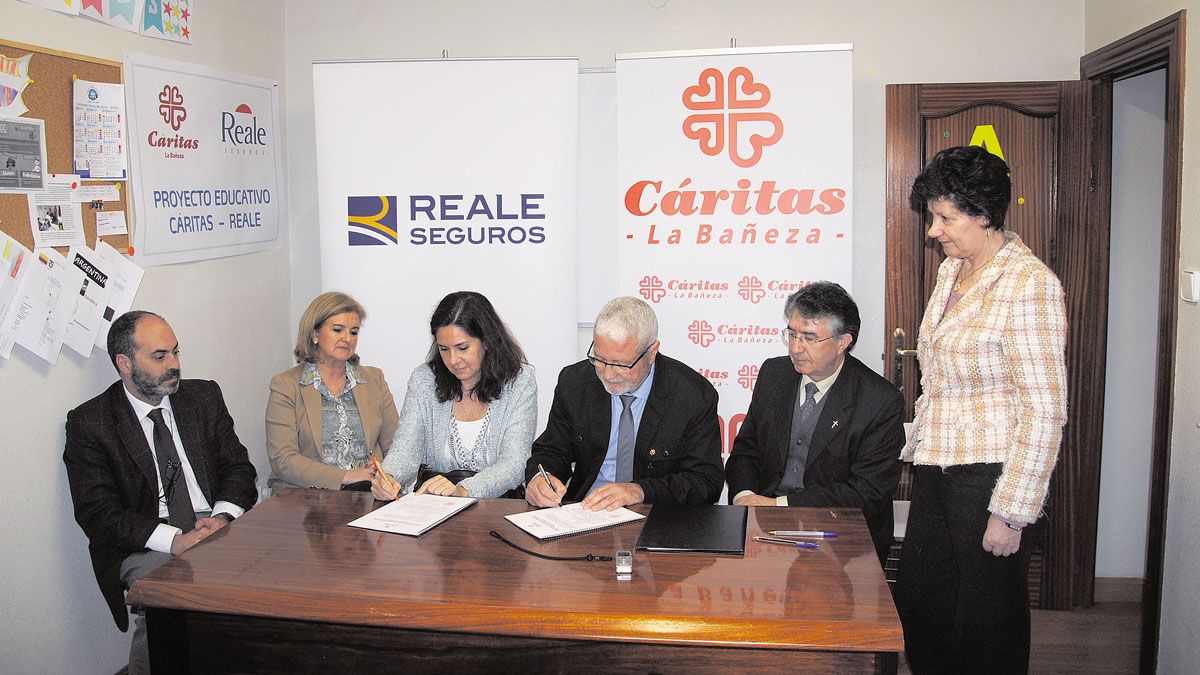 Momento de la firma del convenio entre Cáritas La Bañeza y Reale. | ABAJO