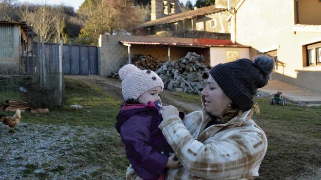 Vivian lleva en brazos a Paula y la abriga, las heladas se están dejando sentir en esta montaña leonesa, como se puede comprobar en el suelo blanco. F. FERNÁNDEZ