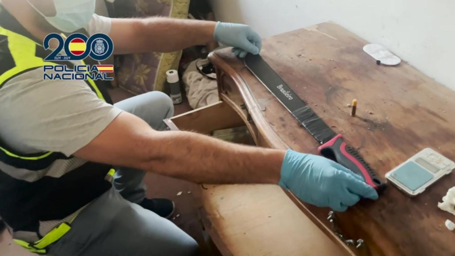 Un agente de la Policía Nacional localiza un machete oculto durante los registros domiciliarios 