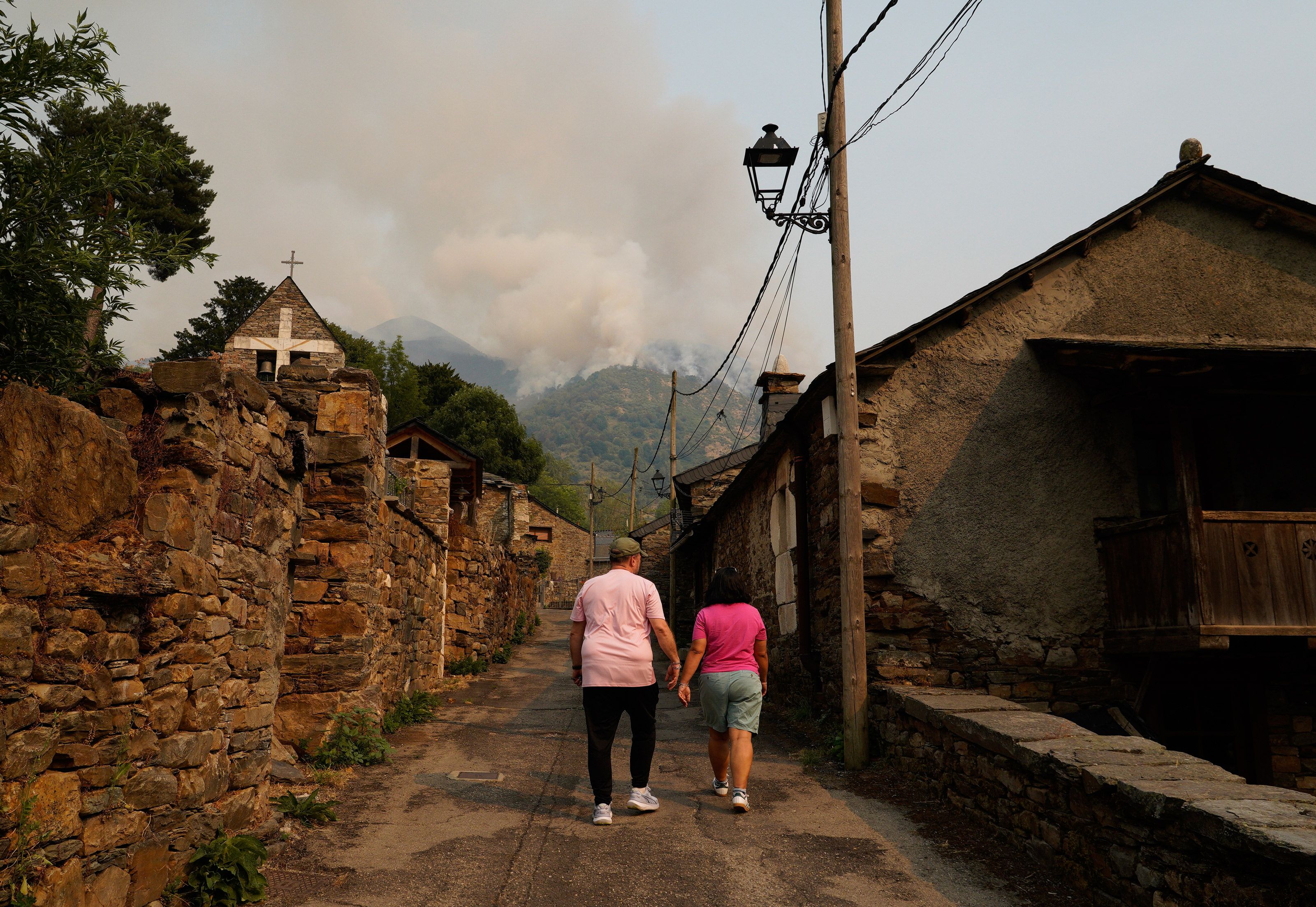 Vecinos de Salientes, con el incendio de Fasgar al fondo, que está metido en Colinas. | CÉSAR HORNIJA (ICAL)