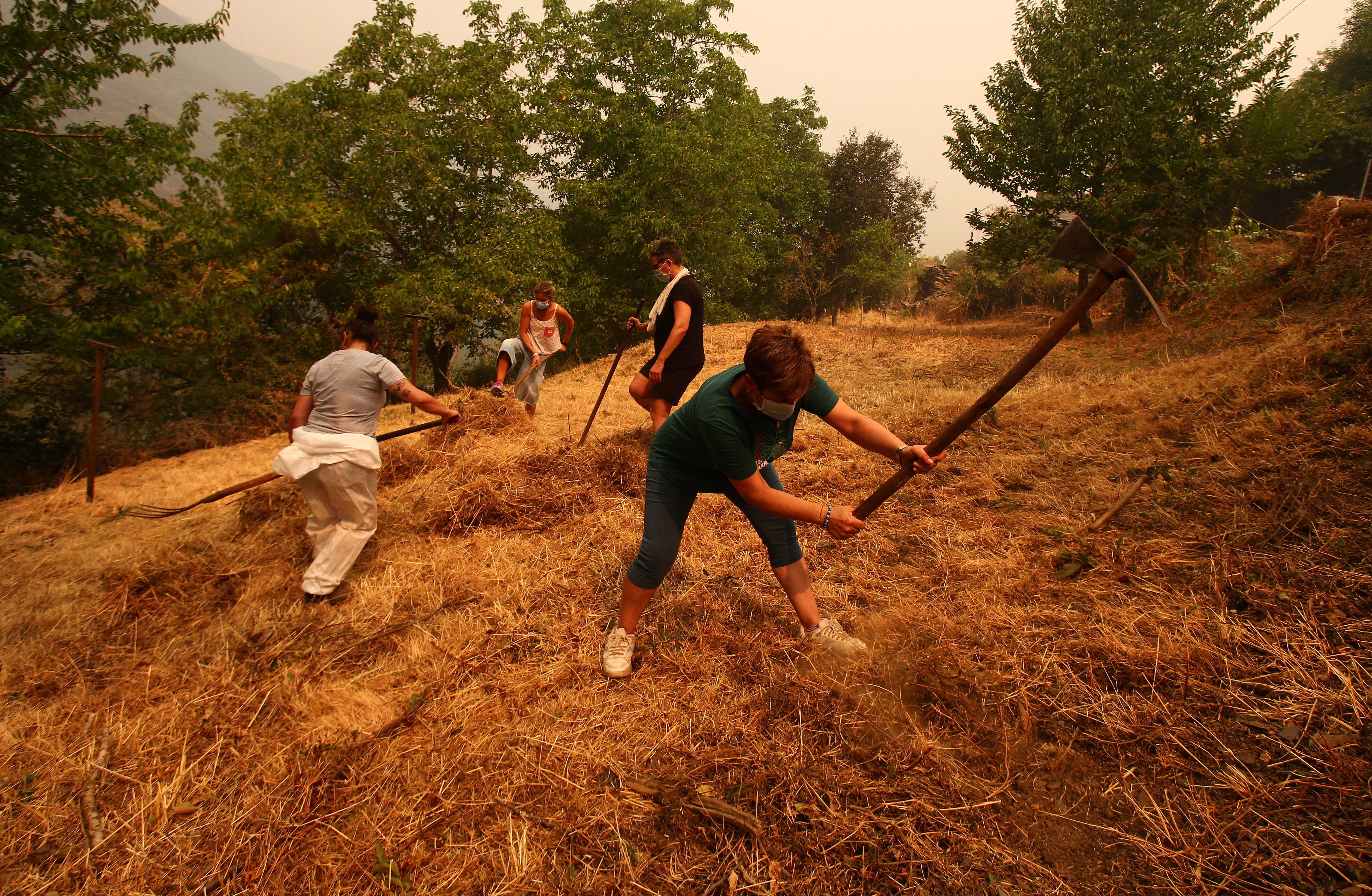 Vecinos de Lusio (León), realizan desbroces alrededor del pueblo ante la posible llegada del incendio. | CÉSAR HORNIJA ( Ical)