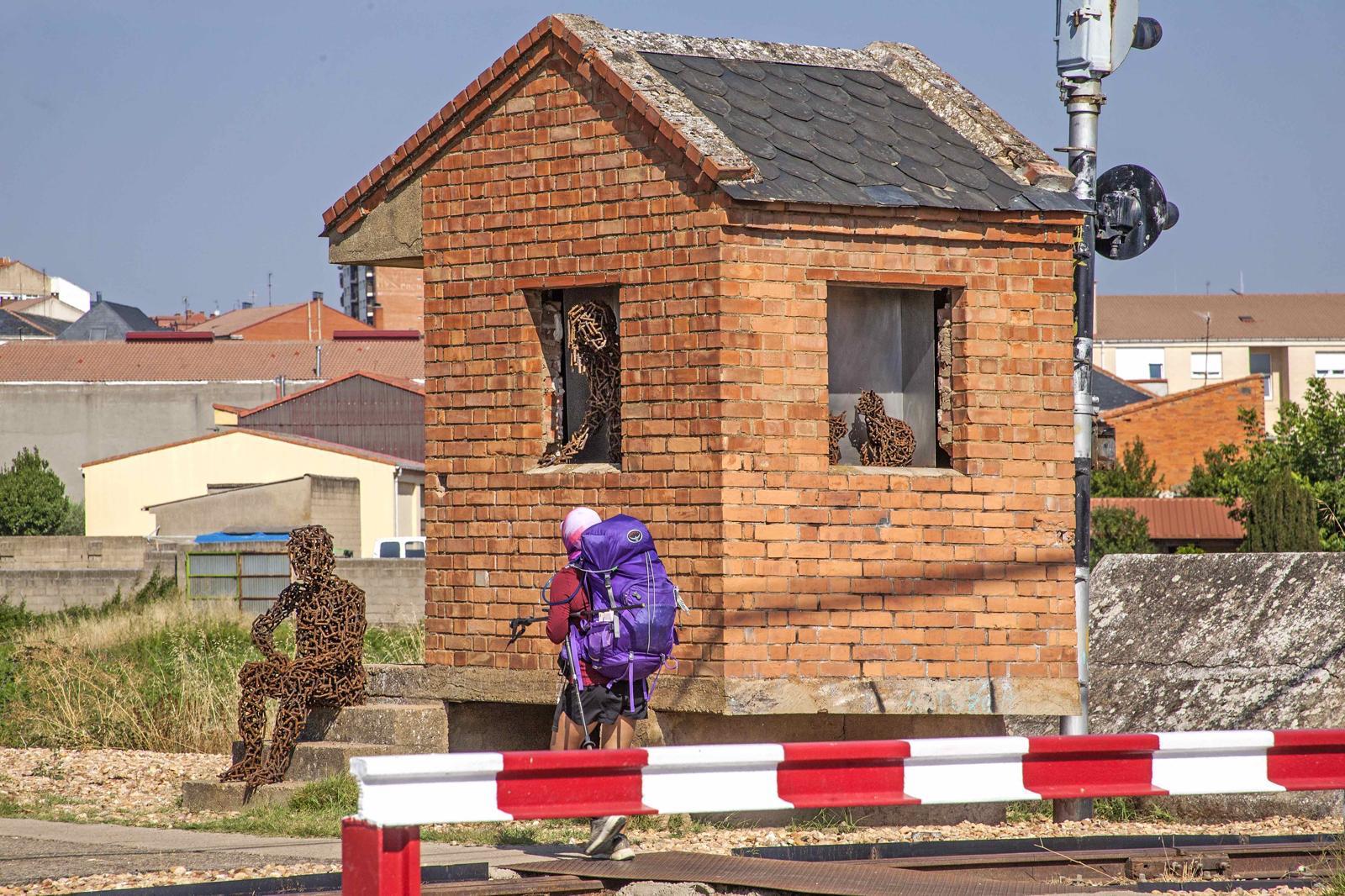 Un peregrino pasando justo al lado de la nueva escultura en la caseta del guarda agujas. | AMANDO CASADO