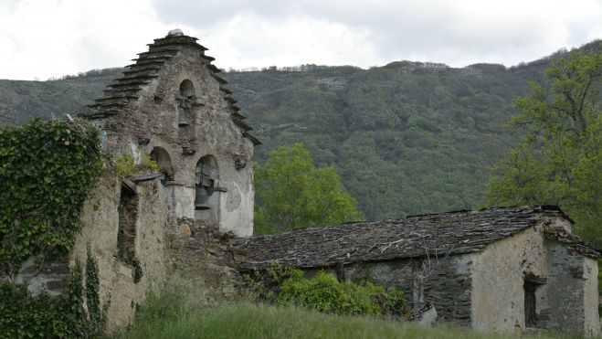 Tras los muros de la casa consistorial, cubiertos de hiedra, la espadaña de la iglesia aún conserva sus campanas Tras los muros de la casa consistorial, cubiertos de hiedra, la espadaña de la iglesia aún conserva sus campanas