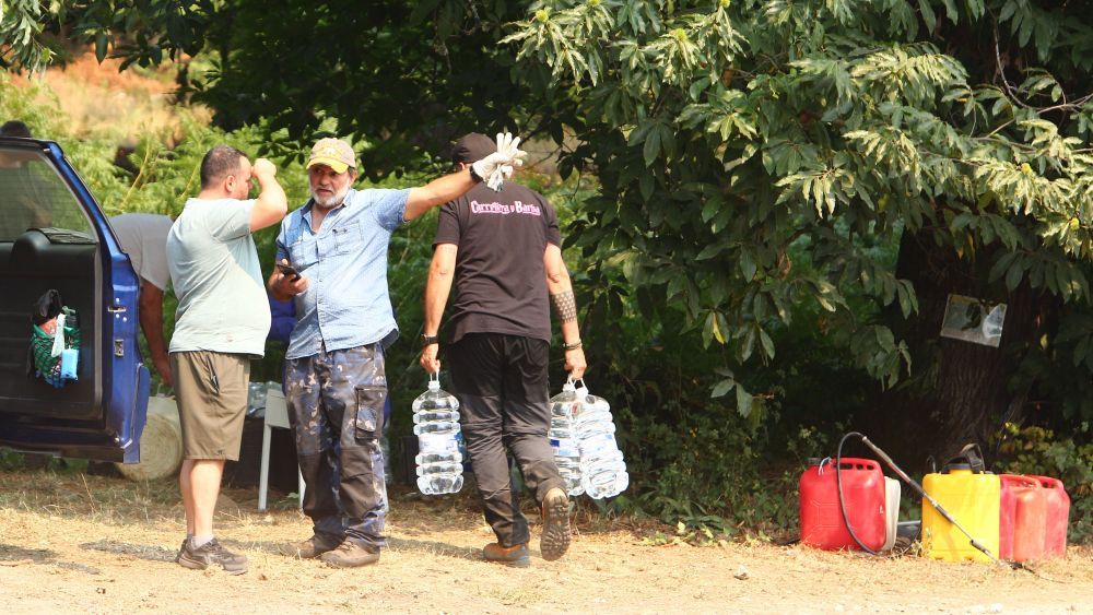 Vecinos ayudando a llevar agua a las zonas afectadas por los fuegos. | CÉSAR HORNIJA (ICAL)
