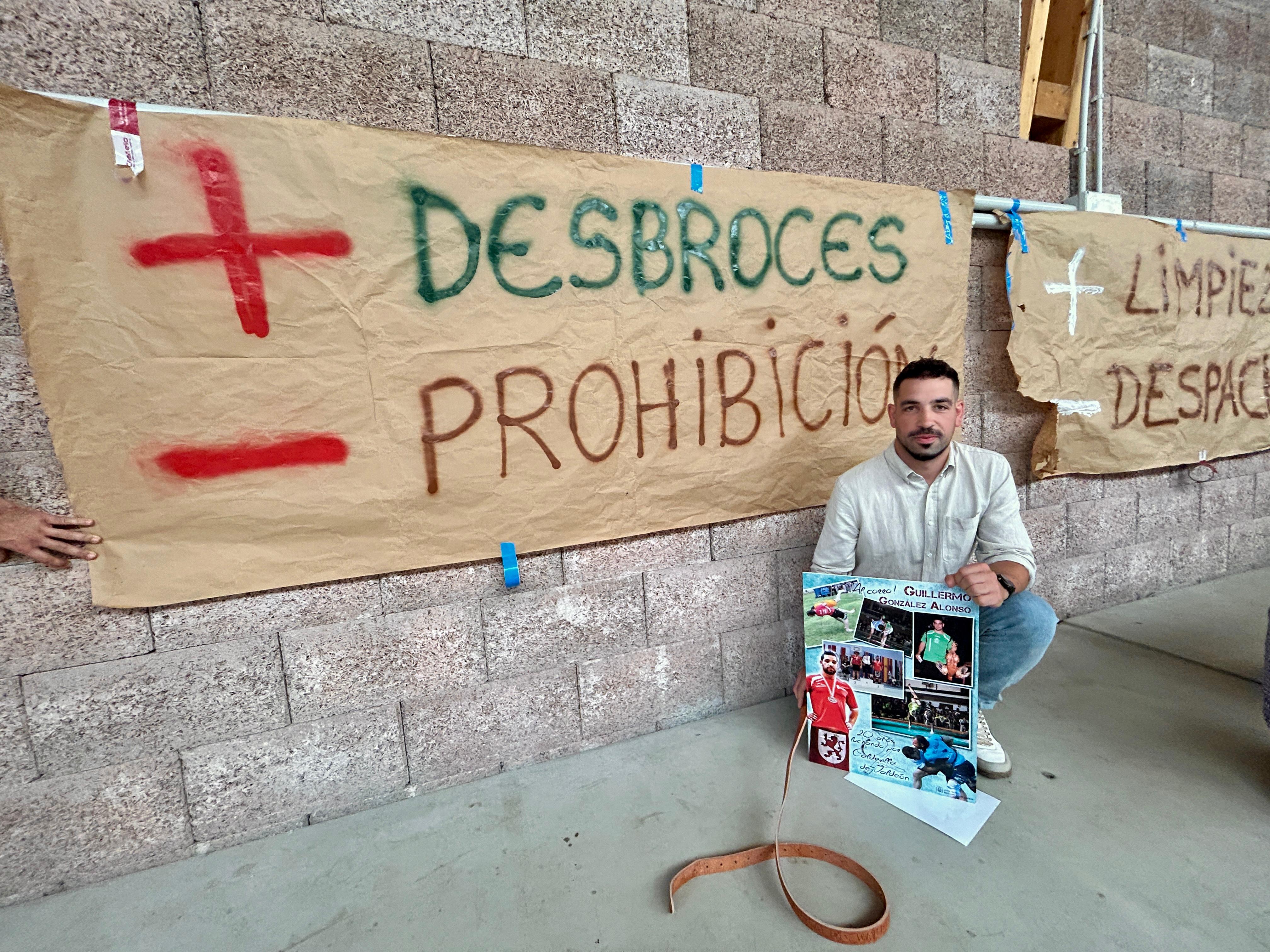 Guiller  González, que fue homenajeado ayer, con un recuerdo de su etapa de luchador ante una pancarta que recuerda los recientes incendios LIDIA DE LA VARGA