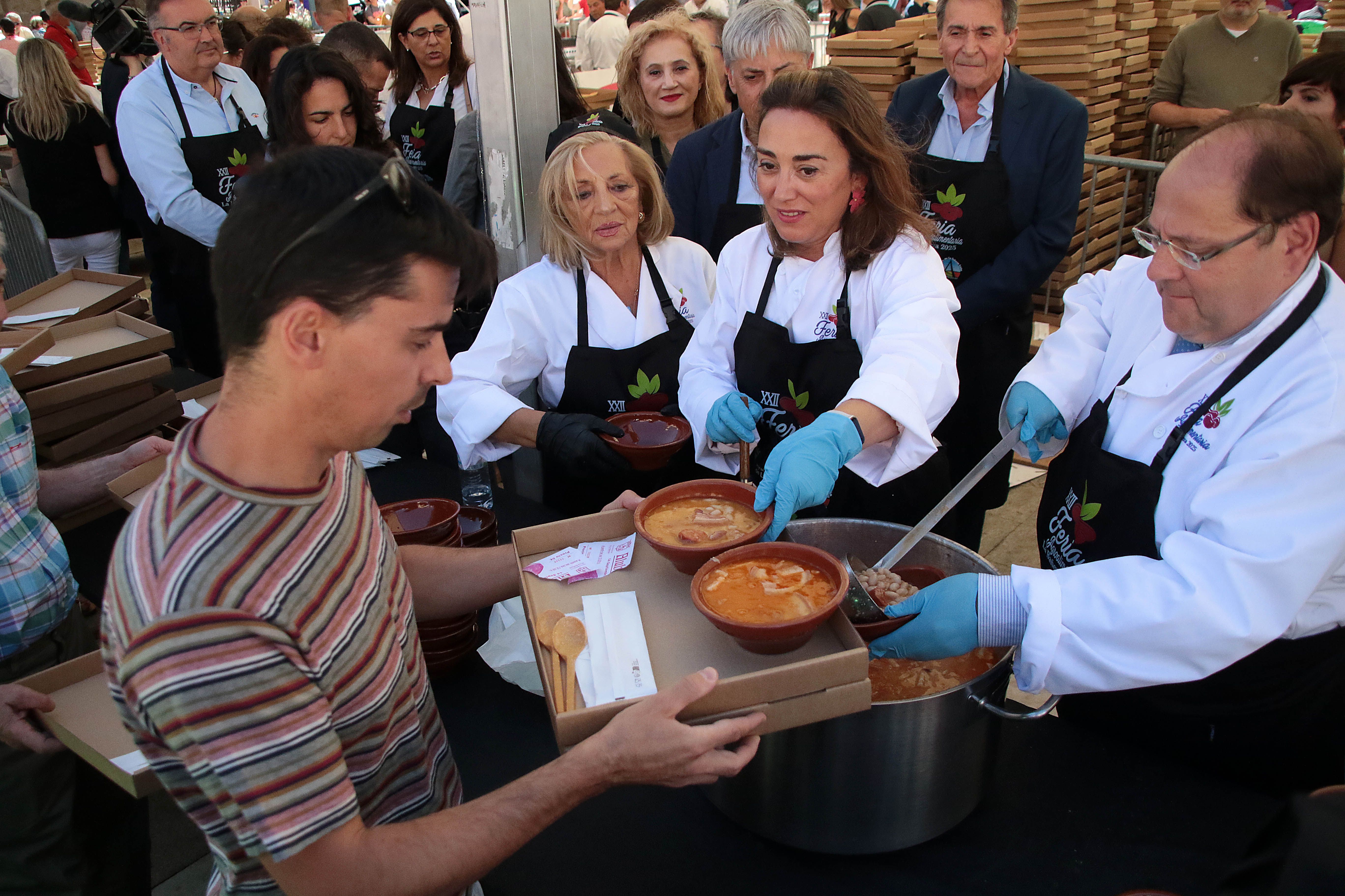 La consejera de Agricultura, Ganadería y Desarrollo Rural, María González Corral, sirve raciones de alubias acompañada por el alcalde, Javier Carrera. | PEIO GARCIA (Ical)