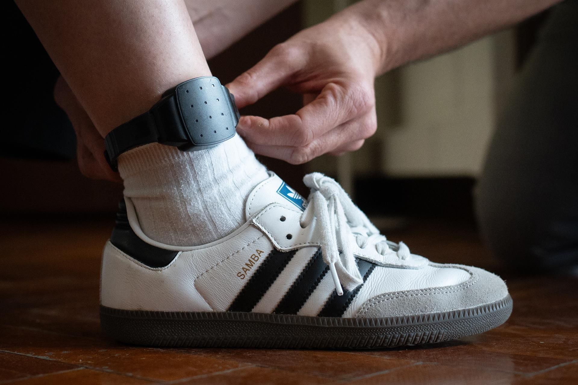 Una persona le coloca a otra una pulsera electrónica de geolocalización telemática. | EUROPA PRESS