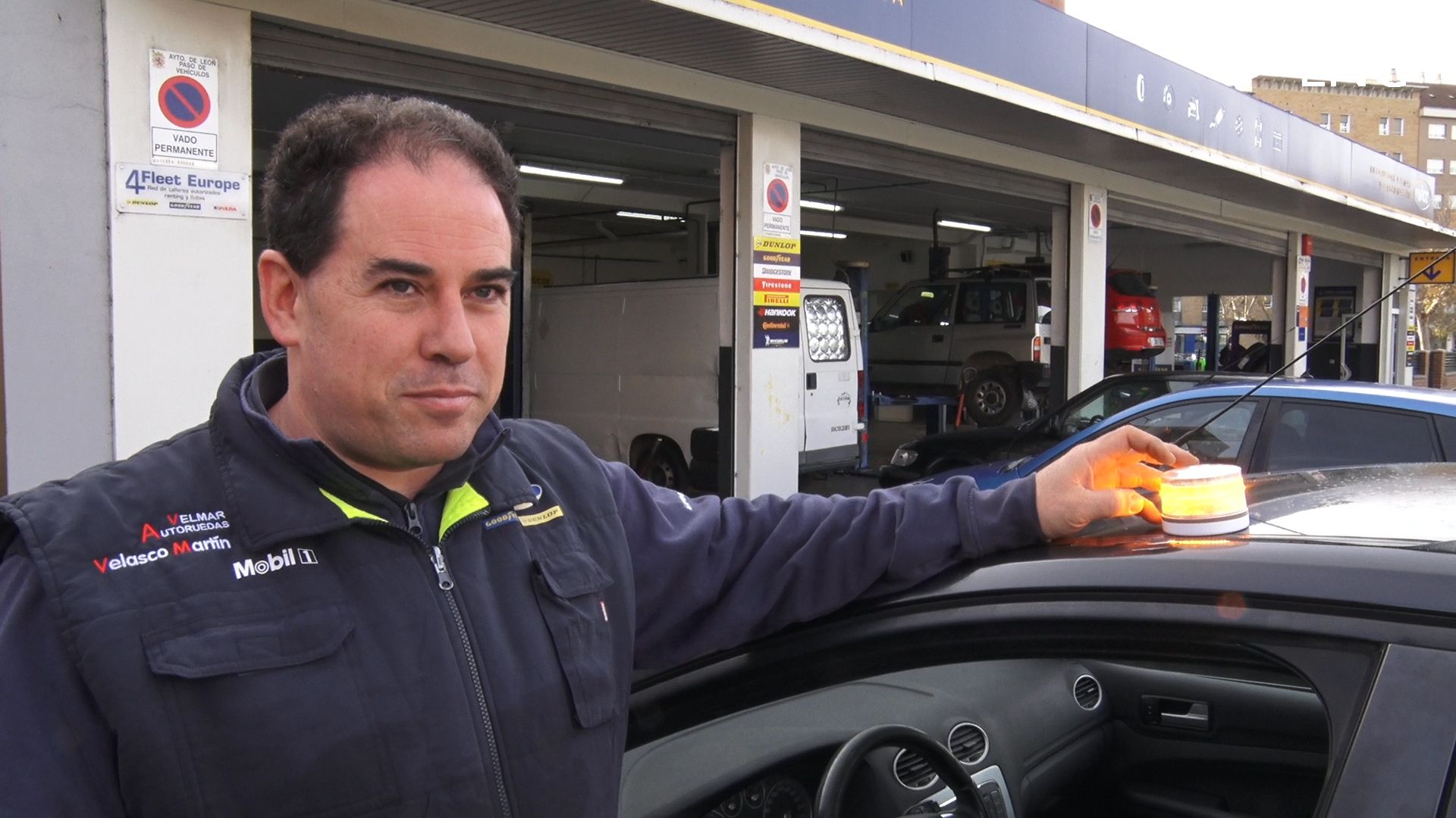 Fran, de Talleres Velasco, coloca la báliza V-16 en un coche. | L.PASTORIZA