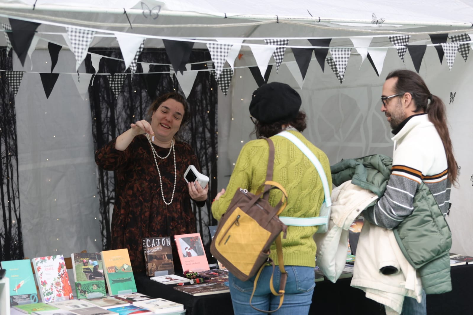 Una mujer atendiendo en su puesto a dos clientes.| FERNANDO OTERO