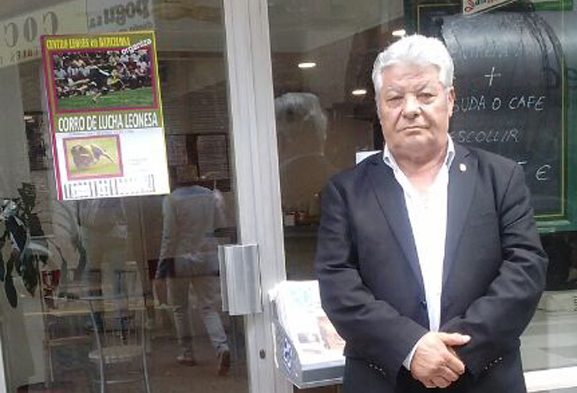 Joaquín González Llamazares, de Gallegos de Curueño, ante el cartel de uno de los corros de lucha que organizó y con algunos leoneses que asistieron al mismo.