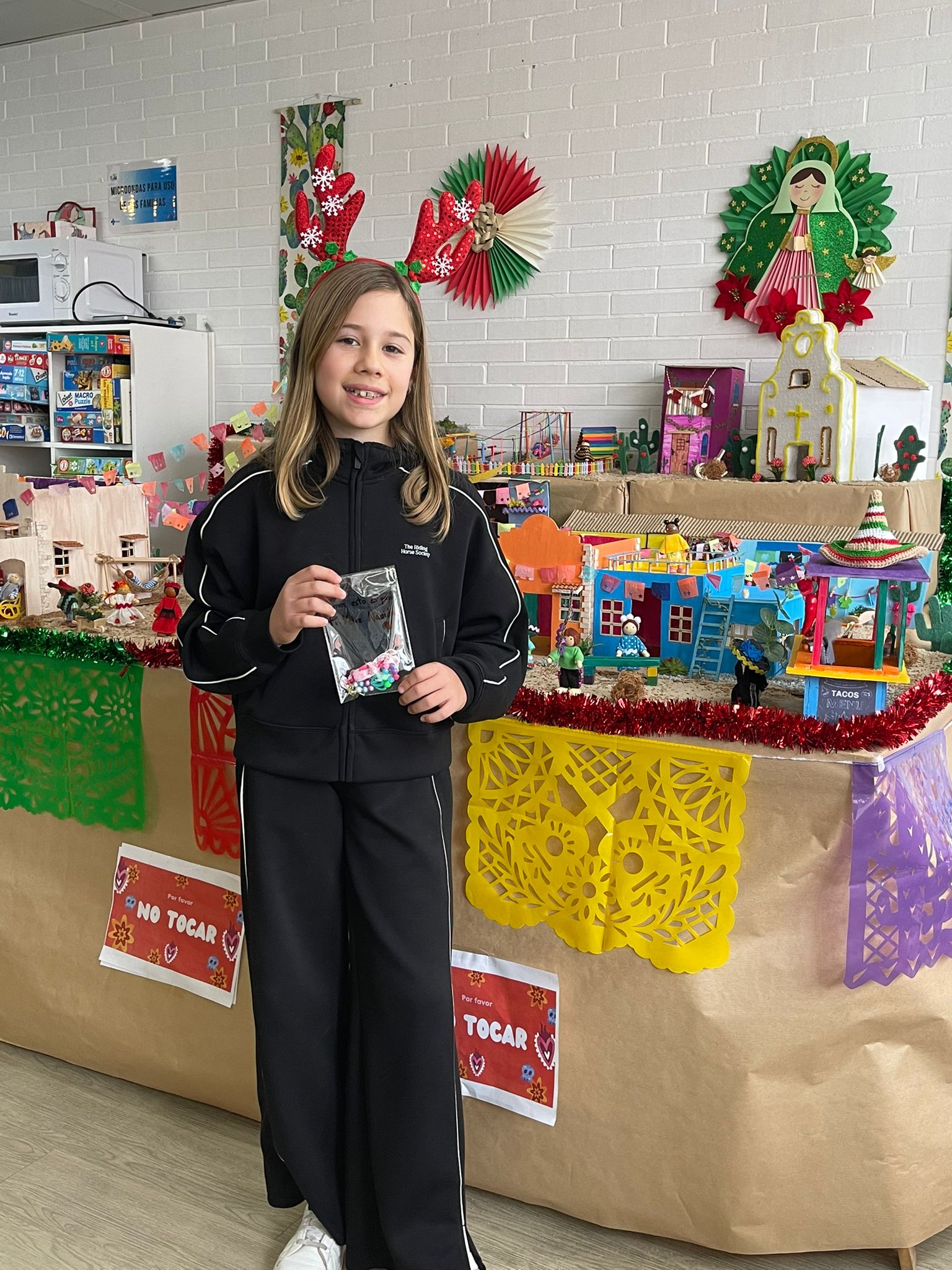 Adriana con una de sus pulseras hechas a mano frente al belén de la Sala de Juegos de Pediatría de la Gasbi.