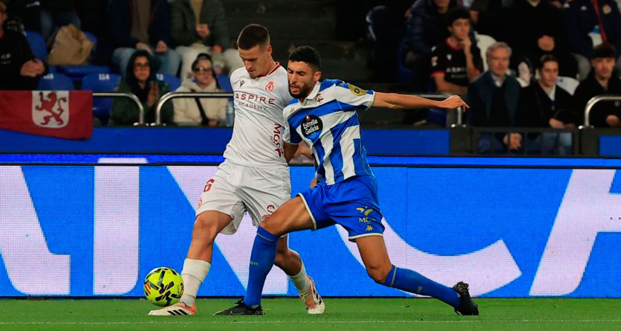 Banderas de León en la grada mientras Barzic pugna por un balón dividido en el Deportivo - Cultural de la primera vuelta. | LALIGA