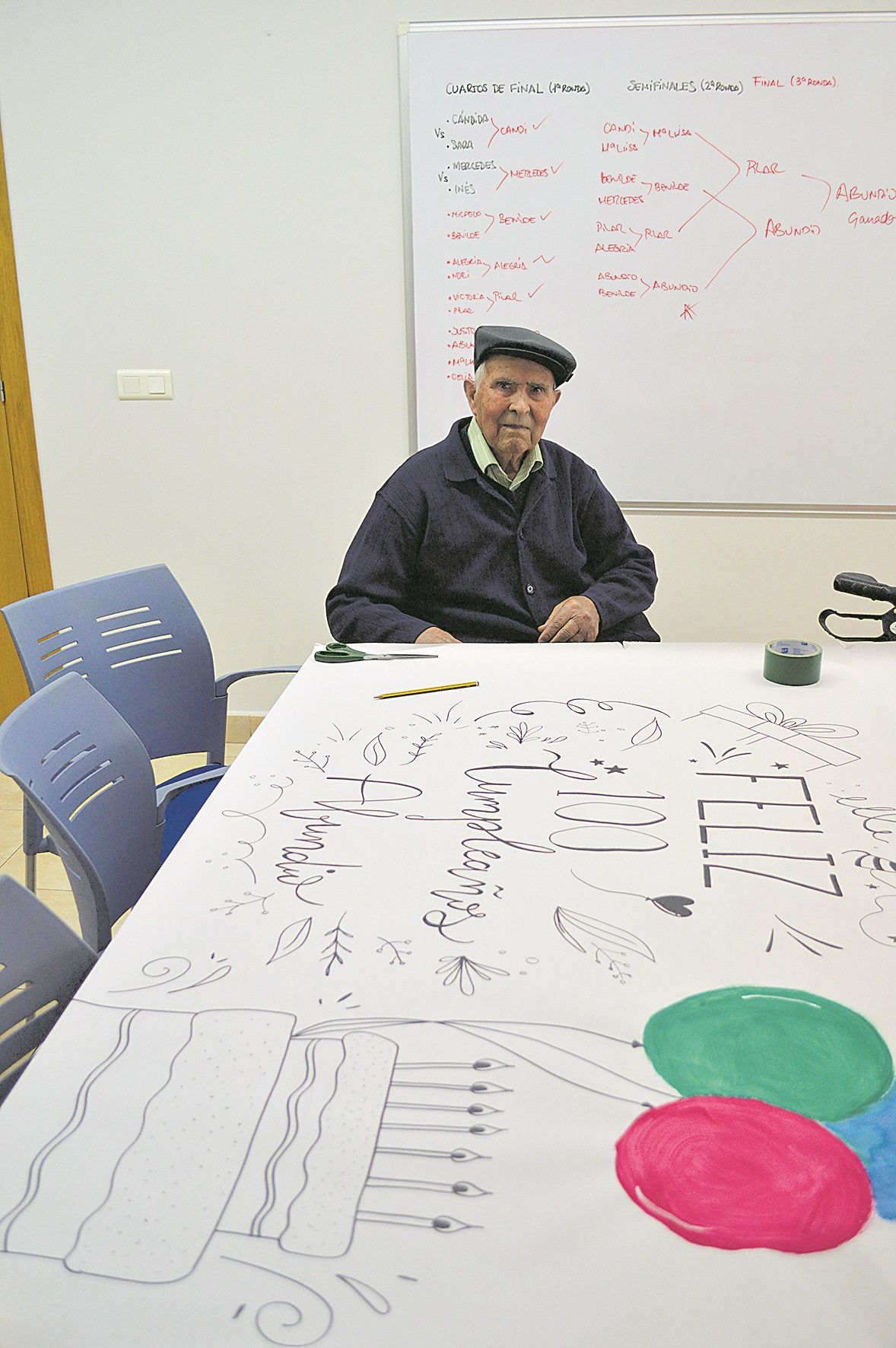 Abundio ante el mural que los trabajadores de la residencia le preparan para su centenario. | F. FERNÁNDEZ