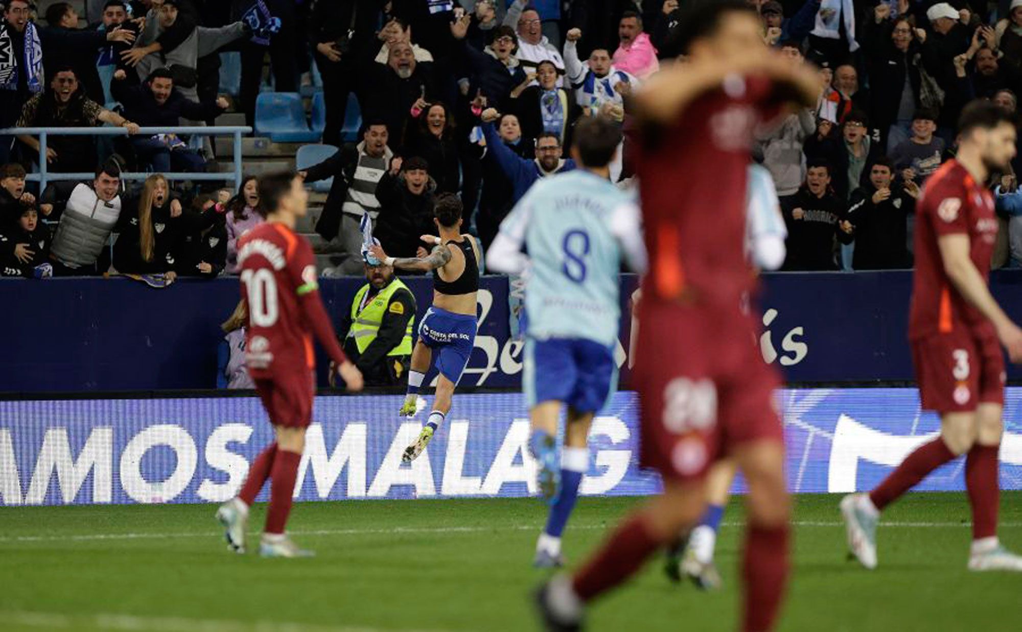 Rostros cabizbajos en la Cultural mientras Larrubia celebra el gol que dio el triunfo al Málaga. | LALIGA