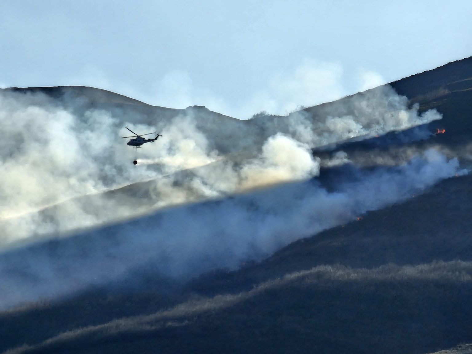 Un helicóptero intenta atajar las llamas en Lomba.