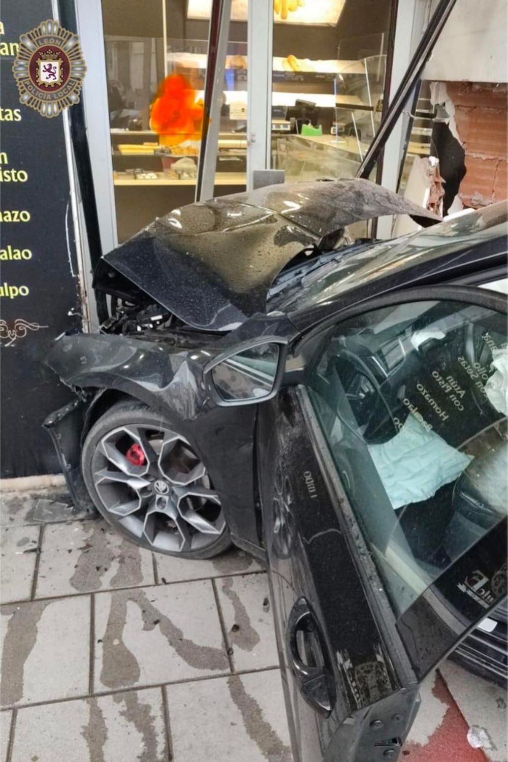 El turismo tras colisionar contra el local de Panadería Rey Dulce en en la confluencia de Padre Isla con Cruz Roja | POLICIA LOCAL DE LEÓN 