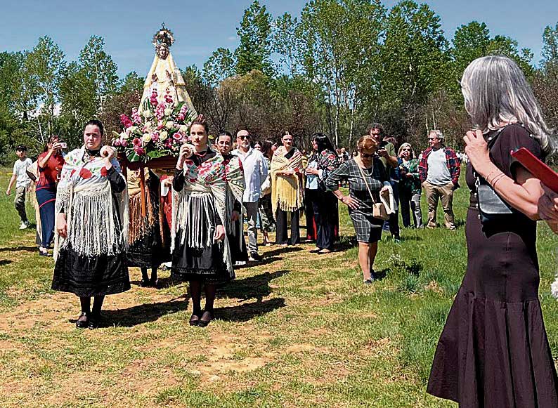Las jóvenes de San Esteban de Nogales lucen las mejores galas para acompañar la procesión que atraviesa el puente de los palos camino de la ermita. | AYARZA