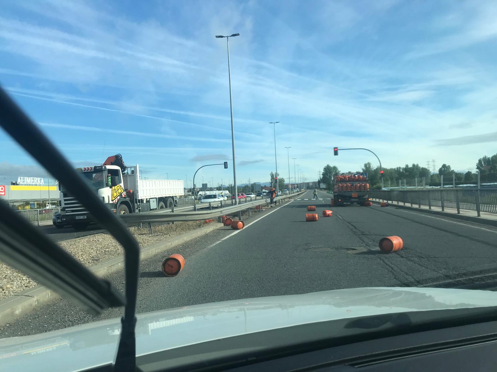 Un camión de butano, tras caer en un bache en la rotonda de La Granja en León, ha provocado la caída de varias bombonas de gas sobre la calzada este lunes por la mañana | L.N.C.