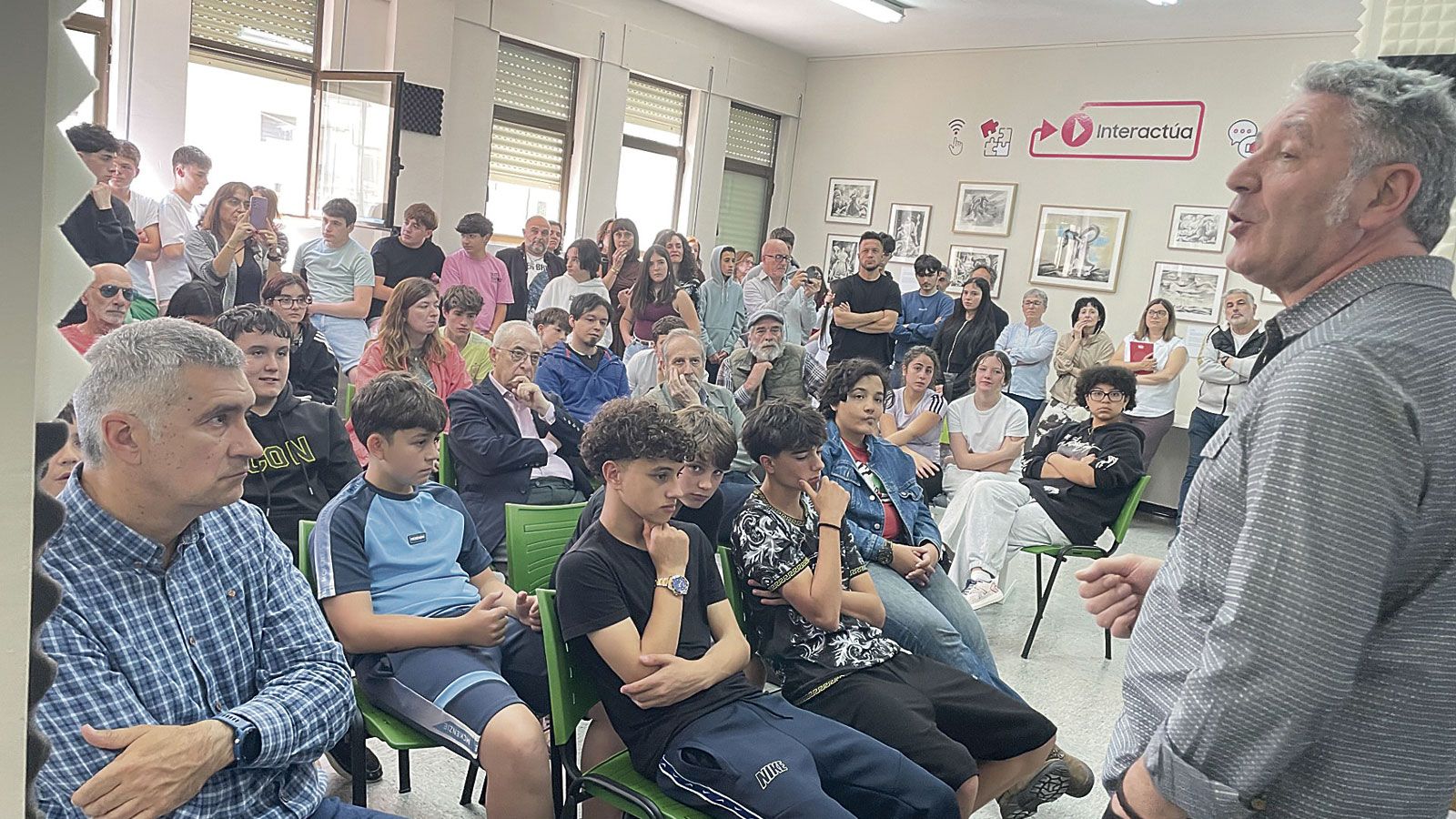 Toño Benavides explica a los alumnos y profesores del IES de Boñar la exposición de sus ilustraciones sobre ‘Mitología Leonesa’. | F. FERNÁNDEZ