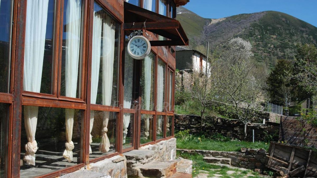 La fachada de los apartamentos turísticos Mil Madreñas Rojas en Salientes, con las montañas del Alto Sil al fondo.