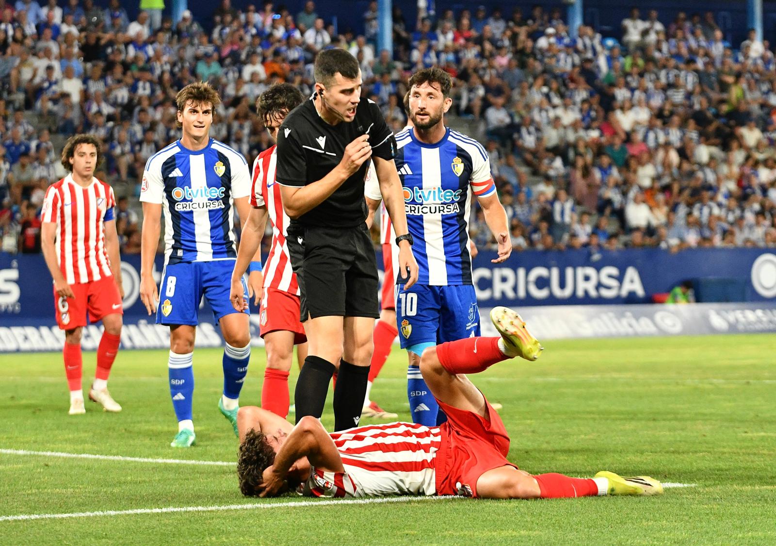 Un jugador del Atlético Madrileño se duele en el suelo ante la protest de Borja Valle al colegiado. QUINITO