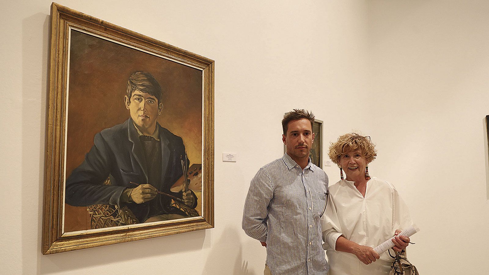 El hijo de Sendo, Nuno, y su viuda, Marisa, junto a un autorretrato (una de sus primeras obras) realizado por el artista de San Justo de la Vega. | FERNANDO OTERO