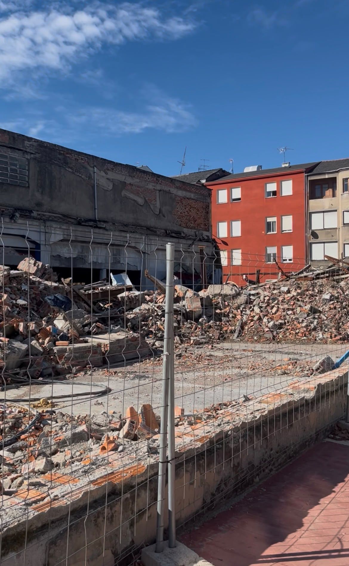 Los cascotes que cayeron del derrumbe del garaje Garnelo siguen en la calle, detrás de las vallas.   L.N.C.