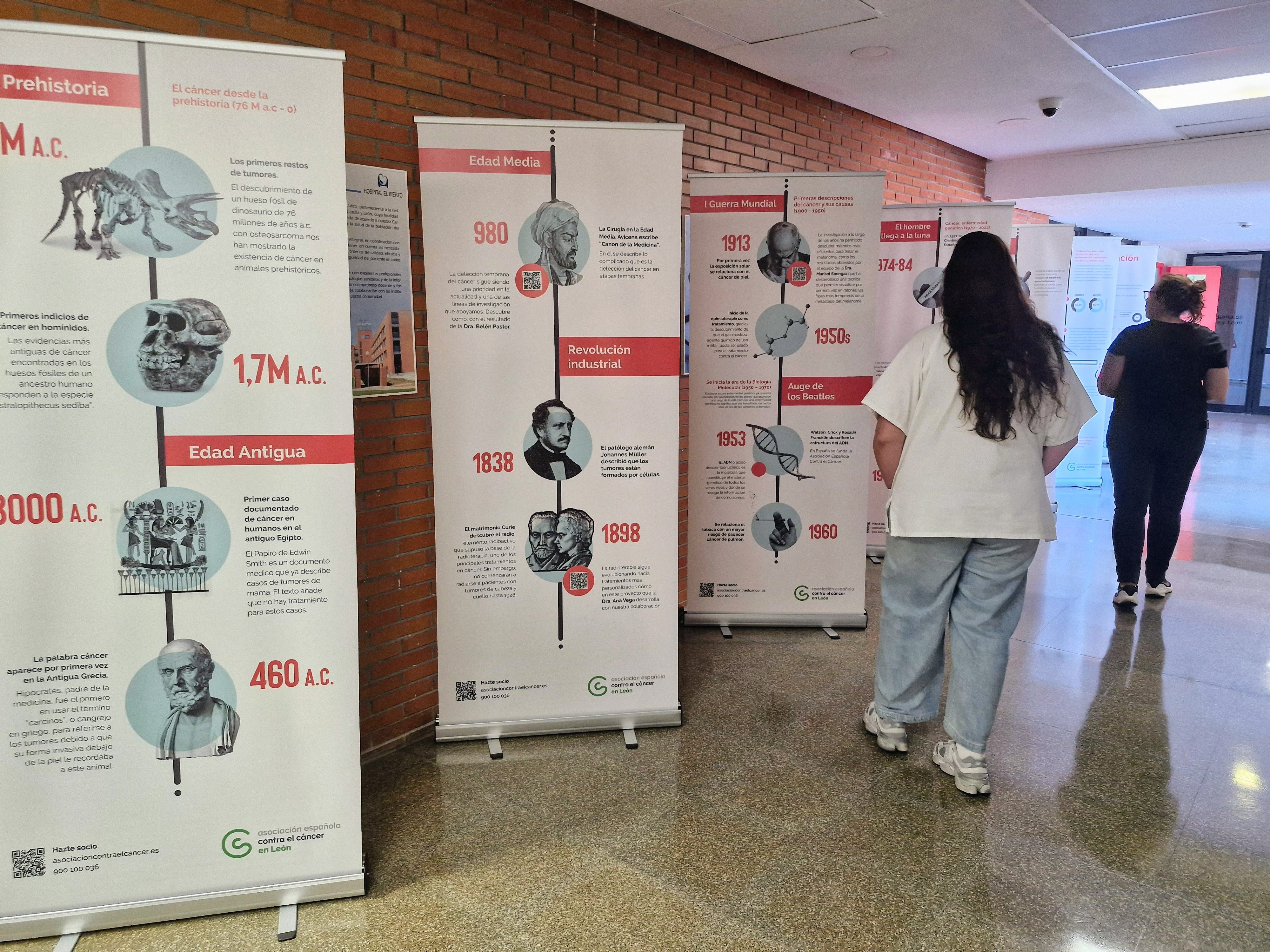 Dos personas observan la exposición de la Asociación Española Contra el Cáncer en el Hospital El Bierzo.