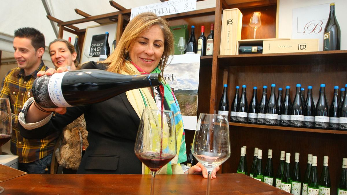 Una mujer sirve una copa de vino del Bierzo durante una feria celebrada en la comarca. | CÉSAR SÁNCHEZ (ICAL)