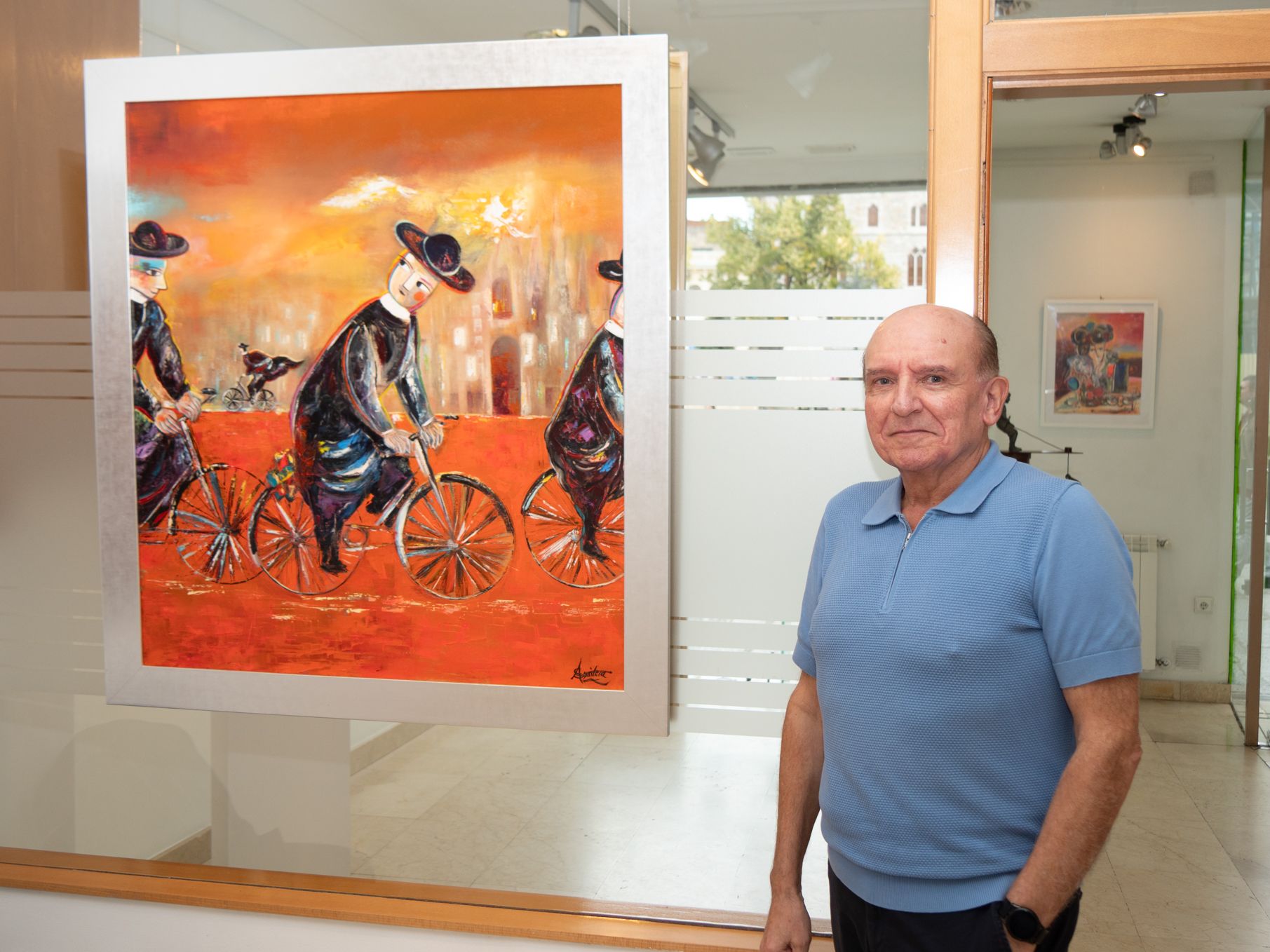 El pintor Sixto Aguilera junto a su obra ‘Curas a la carrera’.  | VICENTE GARCÍA