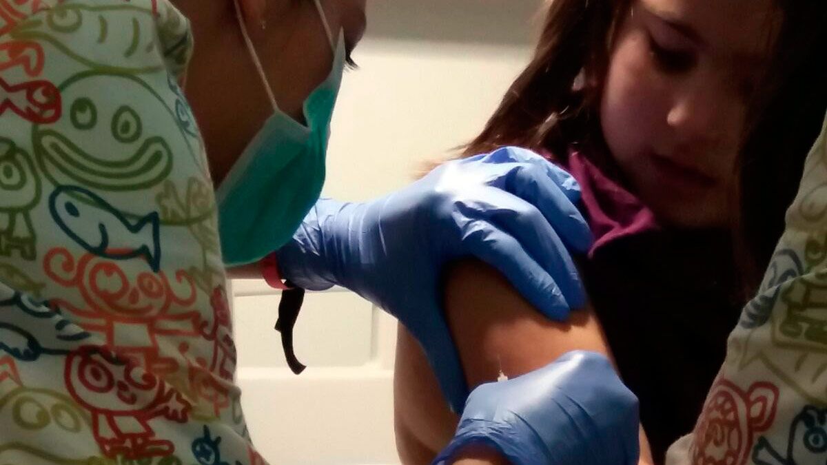 Lucía recibe la primera vacuna ante la mirada de sus padres. | L. CHAMORRO