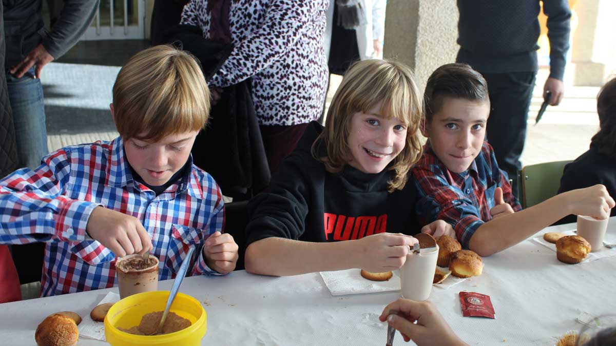 Los niños disfrutando de la leche, el cacao, las magdalenas y las pastas. | A.H.