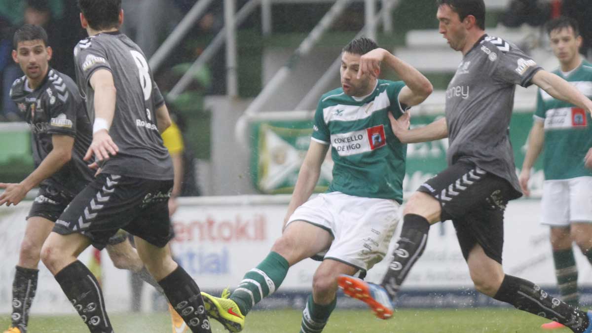 Bardal, Gonzalo yPeláez intentan tapar la salida del balón del Coruxo, levantándose el agua del césped al golpear éste el balón. | FARO DE VIGO