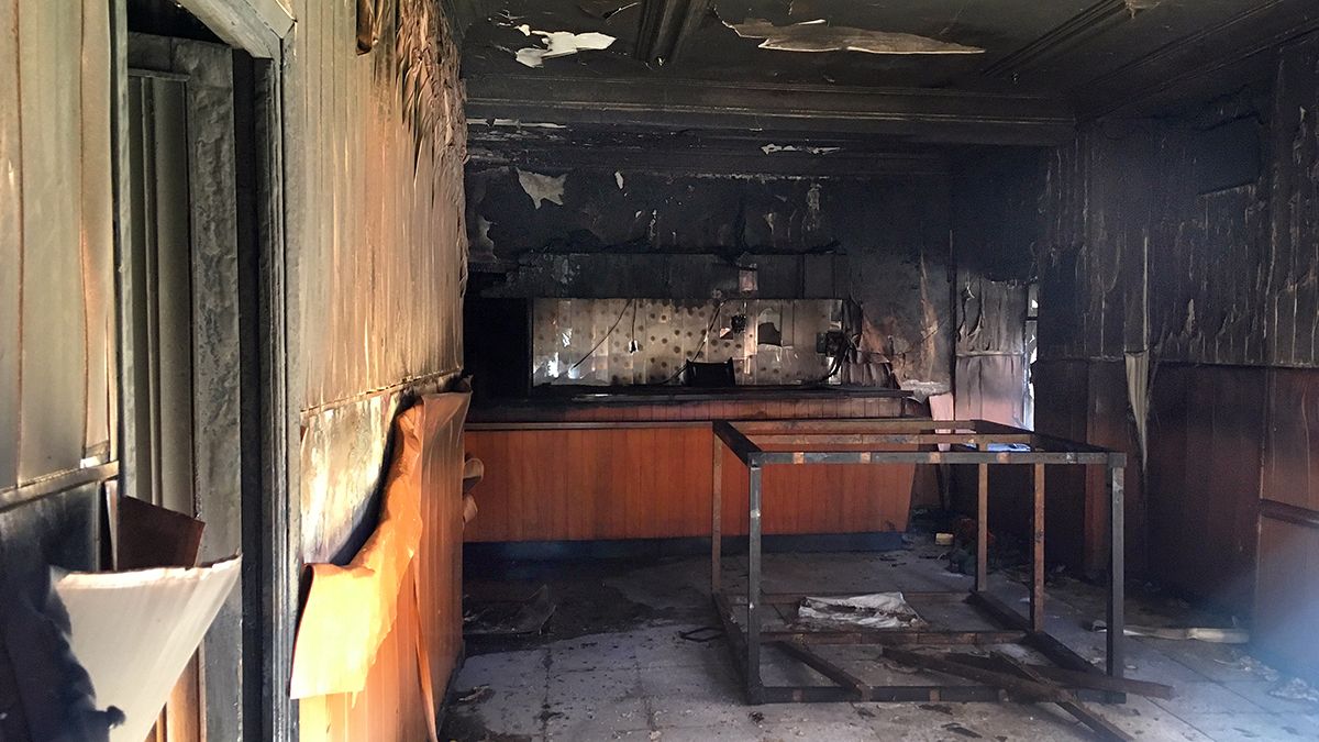 Intervención de los bomberos voluntarios de La Bañeza y estado en el que quedó el interior del antiguo bar. | ABAJO