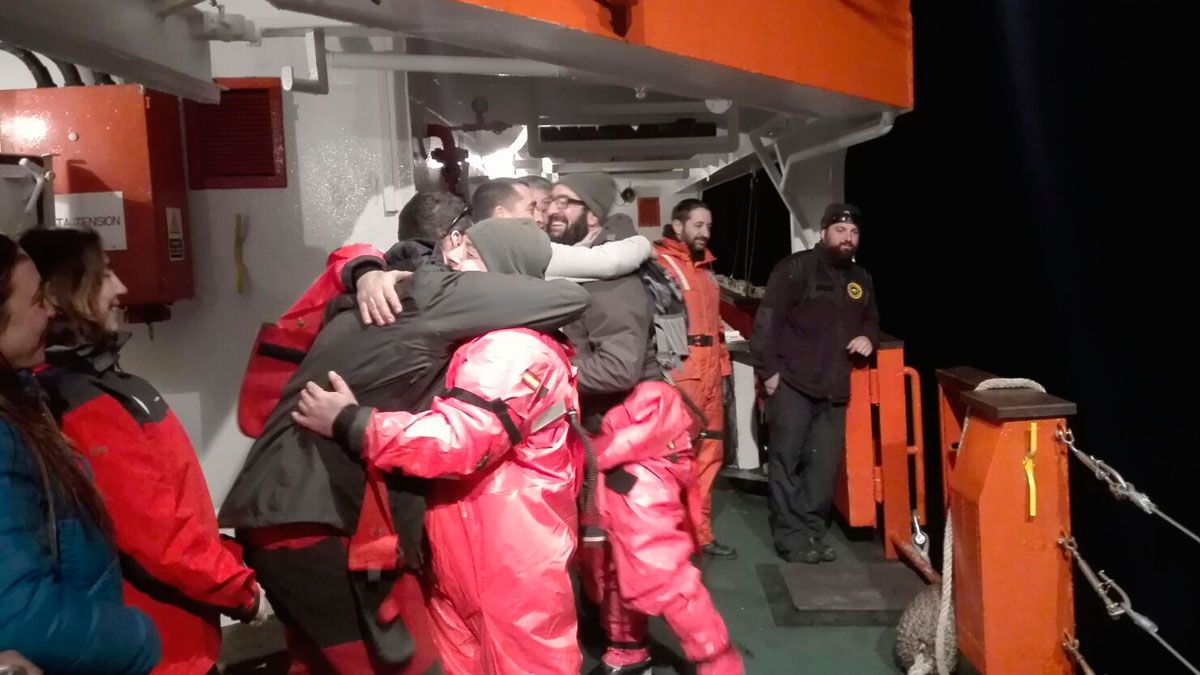 Varios miembros de la expidición se abrazan en cubierta.