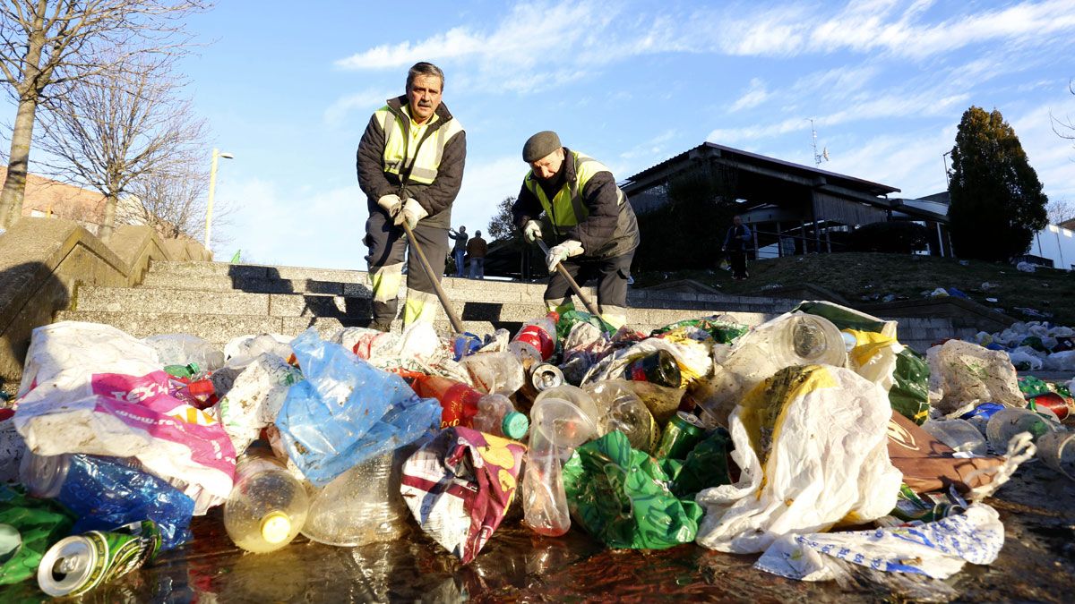 Dos operarios del Ayuntamiento limpiando los restos de basura de la 'espicha'. | ICAL