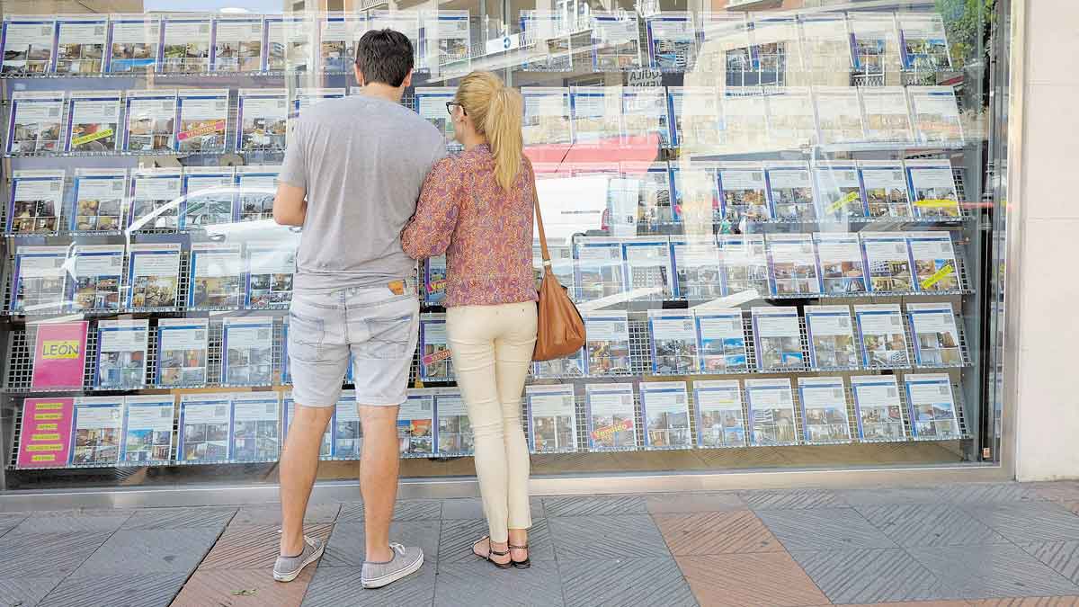 Una pareja mira el escaparate de una agencia inmobiliaria. | DANIEL MARTÍN