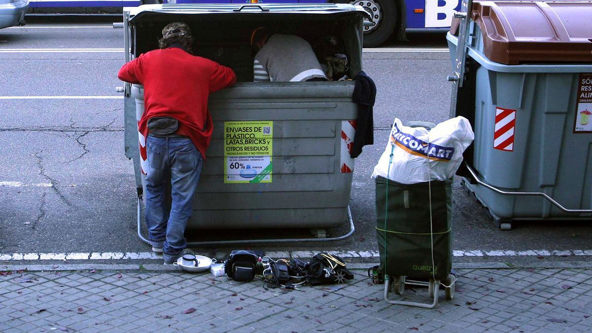 Dos personas rebuscan algo de valor en un contenedor. | ICAL