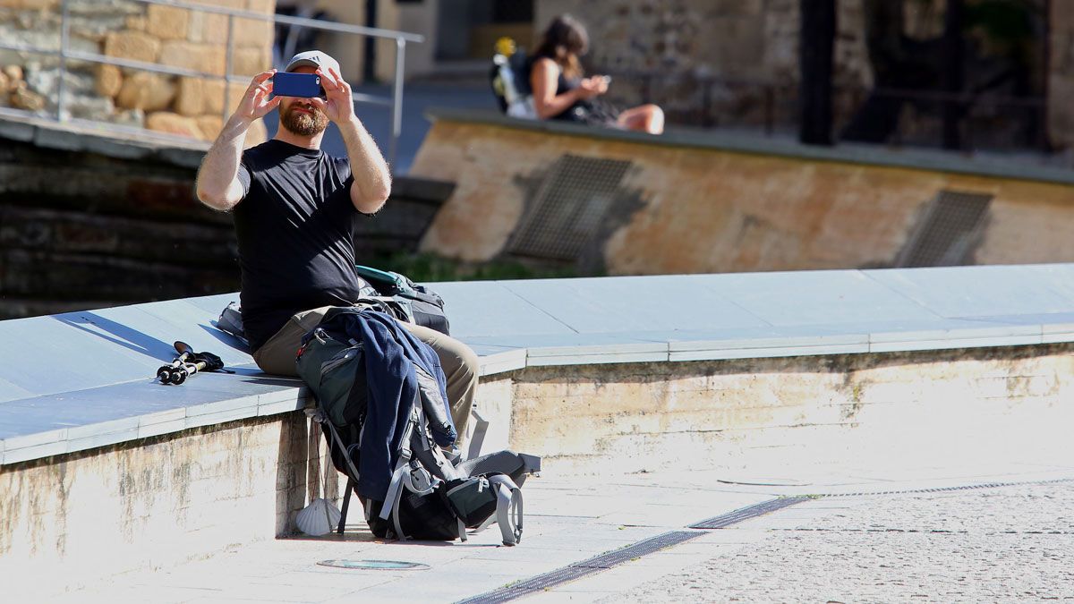 Un turista, sentado realizando una fotografía junto al castillo de los Templarios. | CÉSAR SÁNCHEZ (ICAL)