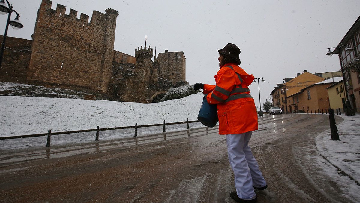 Una operaria esparce sal ante el Castillo de los Tempalrios en Ponferrada debido a la intensa nevada. | ICAL