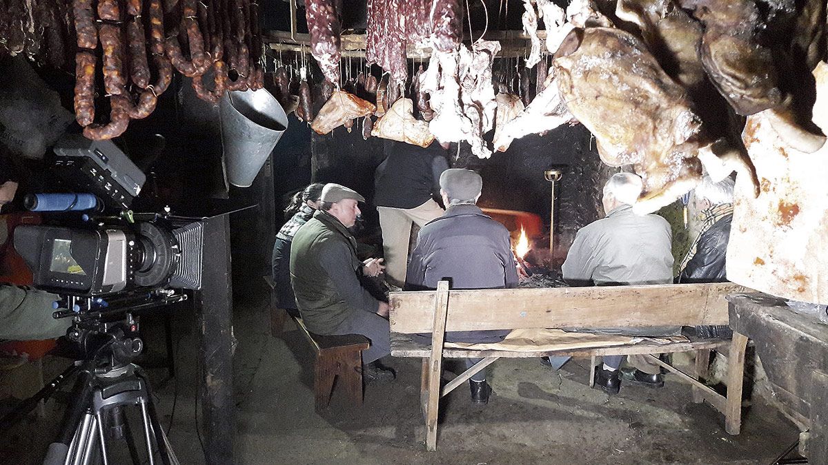 Varias personas celebran en serano en la cocinona de Marzán el de Pombriego, rodeados de la matanza y la palabra.