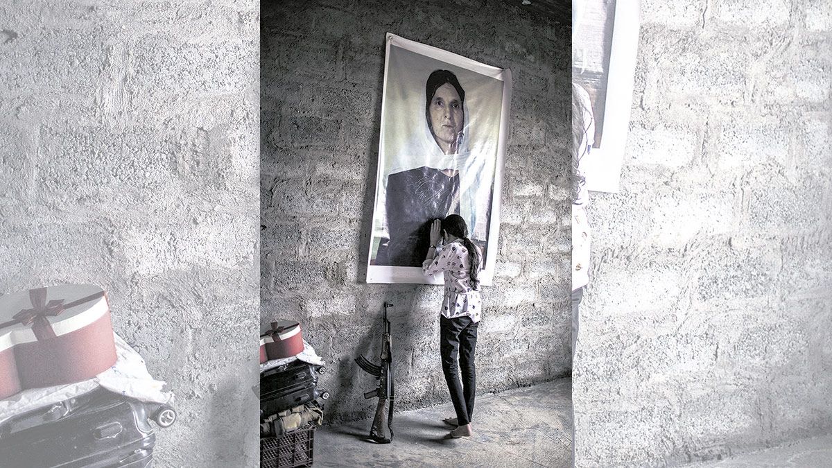 07/05/2018. Sharihan, de 19 años, llora apoyada sobre el retrato de su madre, asesinada por el Estado Islámico, en una habitación de su casa en Sinune.