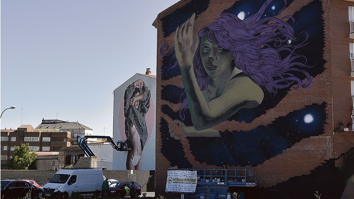 Dos fachadas de edificios de la calle La Vega lucen grandes grafitis visibles desde la carretera Madrid-Coruña, con la mujer como protagonista de las obras. | SAÚL ARÉN
