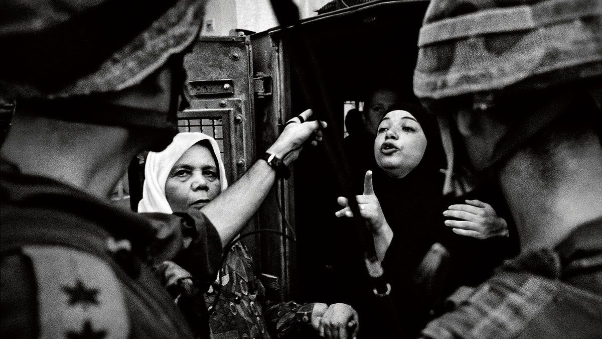 14/09/2003. Una mujer y su madre se enfrentan a soldados israelíes al ser detenidas junto a otro hombre de la misma familia en Qalqilya. | J.M. LÓPEZ
