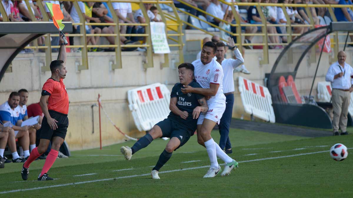 Nicho frena a un jugador del Castilla ante la mirada de Cea. | MAURICIO PEÑA