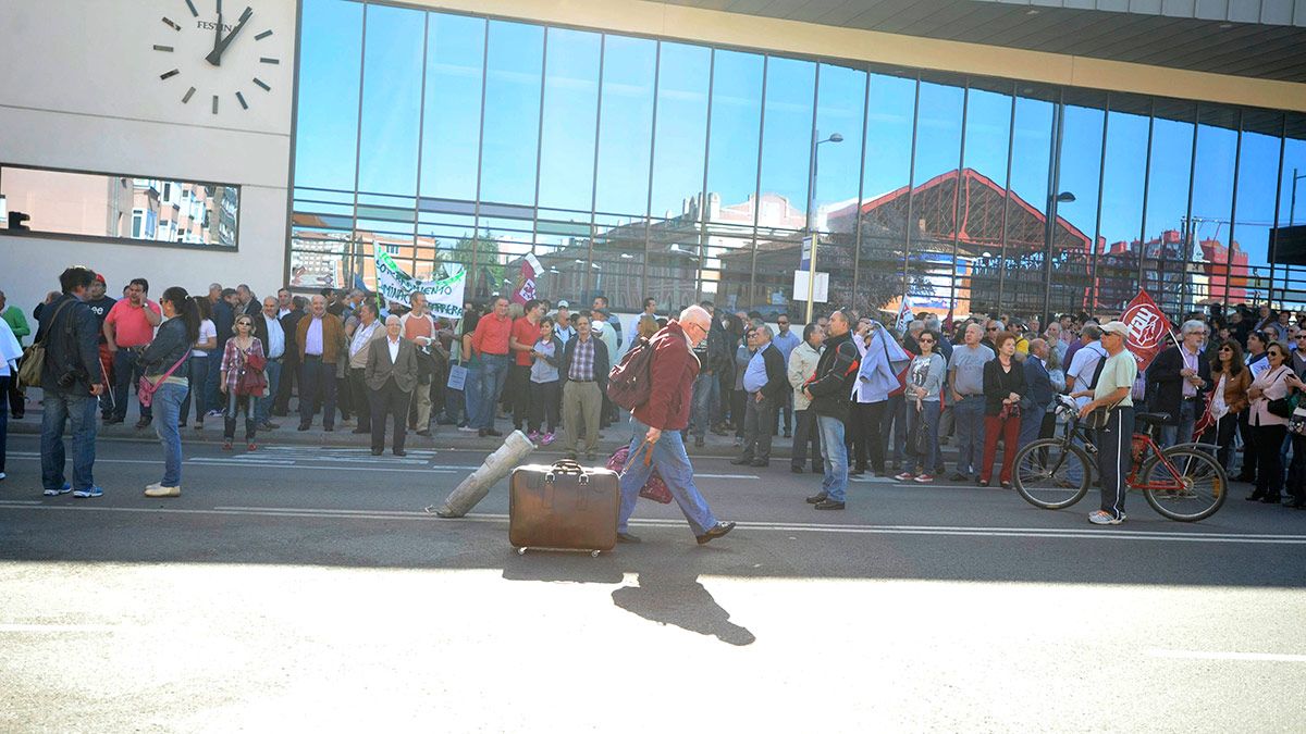 Un viajero cruza ante una manifestación por el servicio ferroviario a las puertas de la estación de León. | DANIEL MARTÍN